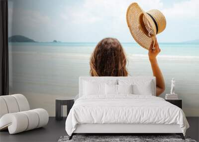 Beautiful young woman raises her hat on a beach Wall mural