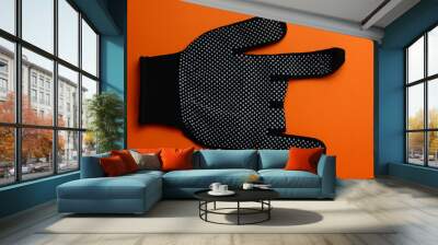 Black work gloves rock and roll gesture, on orange background Wall mural