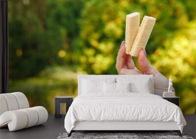 Woman's hand holds waffles, snack and fast food concept. Selective focus on hands with blurred background Wall mural