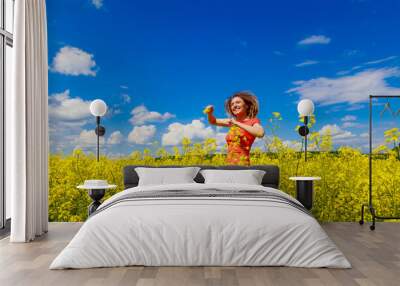 Young pretty woman in a colored dress on Lightning cheerful yellow background blooming rapeseed fields. Wall mural