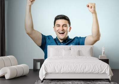 Portrait of happy young man raising his hands Wall mural