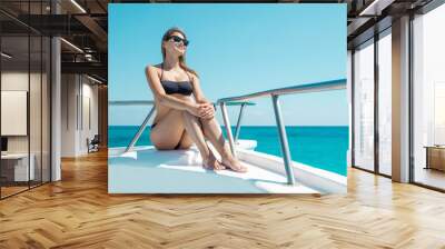 Portrait of hot attractive woman sitting on bow of yacht in bikini Wall mural