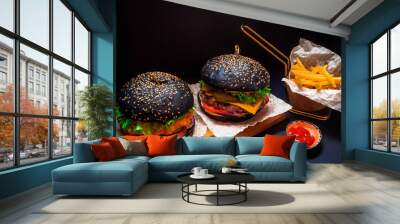 two juicy black burger with crispy fries served in a restaurant on a black background Wall mural