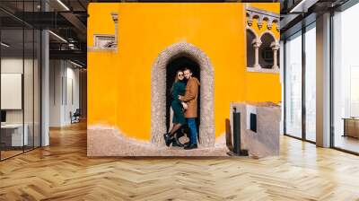 A loving couple stands in the arch of the yellow wall of the beautiful Pena Palace in Portugal Wall mural