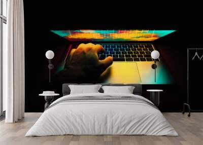 Modern laptop with colored lights on the screen that illuminate the keyboard with one hand on the laptop Wall mural