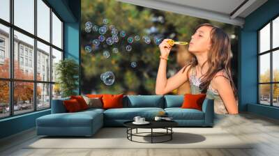 adorable girl blowing soap bubbles in summer park. girl play in park and blowing soap bubbles Wall mural