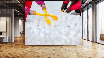 Children with yellow plastic snow ball maker for winter fun on holidays on snow Wall mural