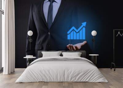 Businessman holding tablet and showing a growing virtual hologram of statistics, graph and chart with arrow up on dark background. Stock market. Business growth, planing and strategy concept. Wall mural