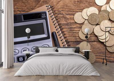 Calculator keypad,gold coins, pen and notebook on a wooden floor background. Top view. Copy space Wall mural