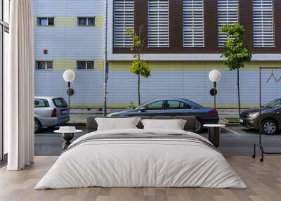 cars parked on the road against a background of a new urban building. a street urban landscape without people, just cars and a building. Wall mural