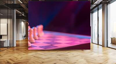 Chess pieces on a chessboard on a dark background shot in neon pink-blue colors. The figure of a chess .Close up. Wall mural