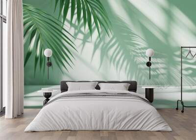 Green palm leaves casting shadows on a light green background with natural sunlight Wall mural