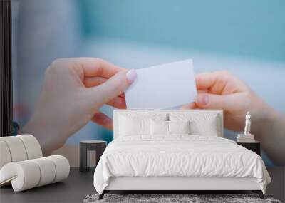 hands of a young woman holding a blank business card mockup, advertisement of different services, business advertisement. Wall mural