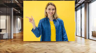 happy girl woman point finger on yellow copyspace making promotion or giving recommendation with sincere emotions. Wall mural