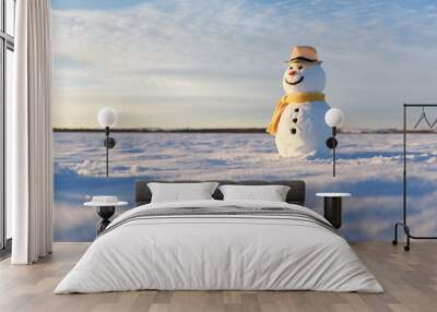 Funny snowman in stylish hat and yellow scalf on snowy field. Merry Christmass and happy New Year! Wall mural