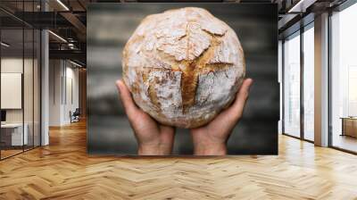 Traditional leavened sourdough bread in baker hands on a rustic wooden table. Healthy food photography Wall mural