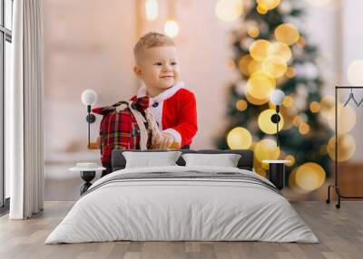 little boy sits on rocking horse and smile. blurred Christmas tr Wall mural