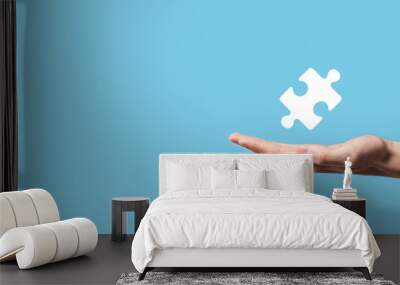 Male hand holding puzzle icon on blue background. pieces representing the merging of two companies or joint venture, partnership, Mergers and acquisition concept. Wall mural