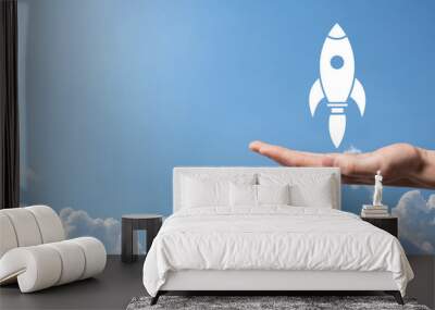 Male hand holding rocket icon that takes off, launch on blue background. rocket is launching and flying out, Business start up, Icon marketing on modern virtual interface.Start up concept. Wall mural