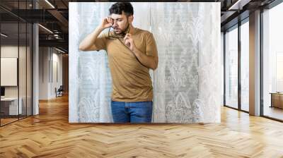 man adjusting glasses with thoughtful expression Wall mural