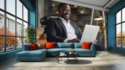 Smiling african american businessman with disability in wheelchair chair using laptop, working despite disability
 Wall mural