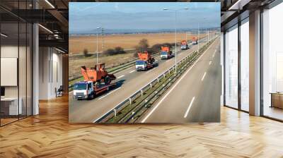 Tow trucks or Flatbed trucks in a convoy towing agricultural or construction machines under a beautiful sky on a highway Wall mural