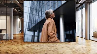 a gray-haired woman head stands inspects the building of a business center Wall mural