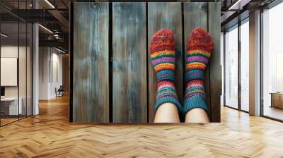 A pair of colorful hand-knitted socks resting on a rustic wooden floor in a cozy indoor setting during autumn. Generative AI Wall mural