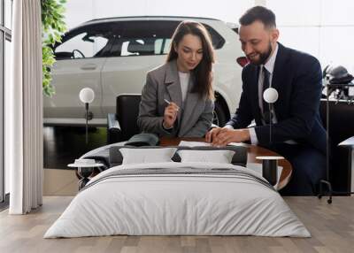 a young woman buys her first car in a car dealership and signs a contract to buy insurance Wall mural