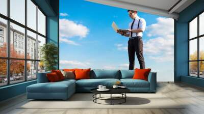 Attractive serious busunessman in white shirt, tie, braces and sunglasses on the roof with laptop Wall mural