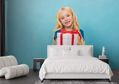 Beautiful caucasian girl holds a white box with gift and has a lot of emotions isolated on blue background Wall mural