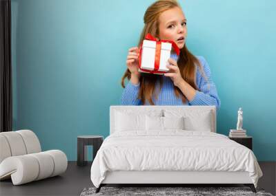 beautiful european girl holding a gift on a light blue wall Wall mural