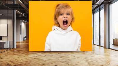 blond boy grimaces on a yellow studio background close-up Wall mural