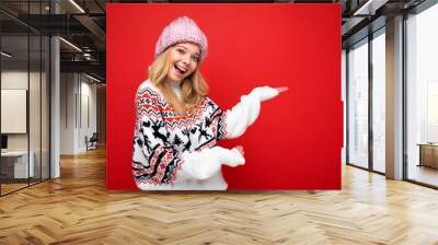 Close up photo of positive happy amazing cute nice charming young woman holding hand and showing advertisement wearing casual clothes isolated over background with copy space. Winter concept Wall mural