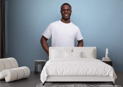 handsome young african man in white t-shirt on blue background with copy space Wall mural