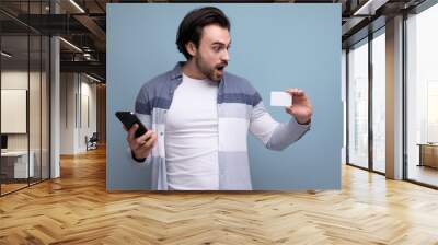 happy joyful brunette guy in casual style pays for purchases with a card Wall mural