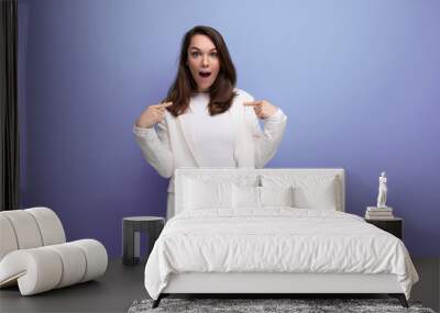 happy lucky brunette woman in ivory jacket and white dress on purple background with copy space Wall mural