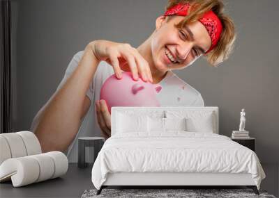 man with pink cute piggy bank on gray background Wall mural