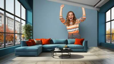 Photo portrait of young pretty beautiful happy positive funny joyful blonde woman with sincere emotions wearing stylish clothes isolated on blue background with empty space and celebrating winning Wall mural