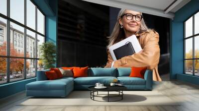 portrait of an elderly businesswoman with a laptop in glasses outside the office, strong and independent woman concept Wall mural