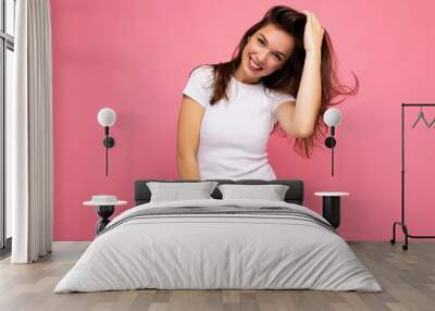 Portrait of positive cheerful fashionable woman in casual t-shirt for mock up isolated on pink background with copy space Wall mural