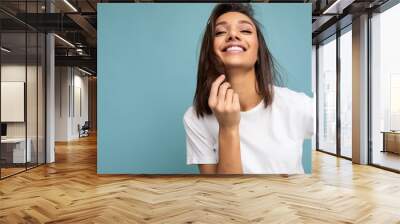 Portrait photo of positive happy smiling young fascinating beautiful attractive nice brunette woman with sincere emotions wearing casual white t-shirt for mockup isolated over blue background with Wall mural