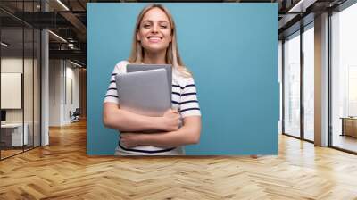 smart successful confident girl student with a laptop in her hands on a blue isolated background Wall mural