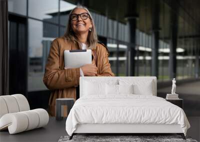 stylish gray-haired adult woman with a laptop in her hands and a wide smile outside Wall mural