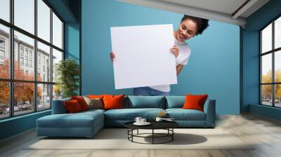 young brunette latin woman in white t-shirt holding a billboard with mockup Wall mural