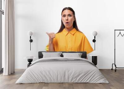 young brunette woman dressed in a summer yellow dress points her finger to the side in surprise Wall mural