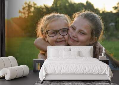 Two little girls sisters hugging. In the yard at sunset Wall mural