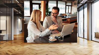 Two young male and female business partners having a meeting in a restaurant. Discussing and planning. Wall mural