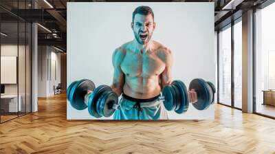 Young man training biceps muscles with dumbbells Wall mural