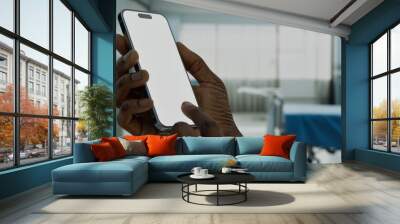 Black African-American male using smartphone with a blank screen in hospital Wall mural